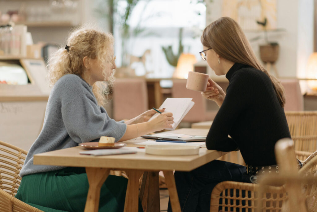 Two women reviewing financial notes during a coaching session.